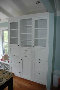 a kitchen with white cabinets and marble counter tops