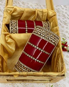 two red and gold bracelets in a wooden box on a white tablecloth covered table