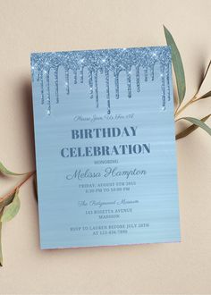 a blue birthday party card with icing on it and greenery next to it