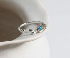 Invoking the gentle summer waves off the Devon coast, this dainty ring features a blue Fire Opal and is finished with our signature 14kt gold details, set on a curving Sterling Silver band crafted from our unique wax form.  Perfect for anyone with an appreciation of coastal jewellery. The graceful intricacy of the design combined with Opal, which is known to be an October birthstone, creates a thoughtful personalised gift. Designed in our Devon studio, our ring is handcrafted with the utmost car Coastal Jewelry, Slim Ring, Blue Opal Ring, Silver Gift Box, Jewellery Unique, Zierlicher Ring, Coastal Blue, Jewellery Handmade, Funky Jewelry