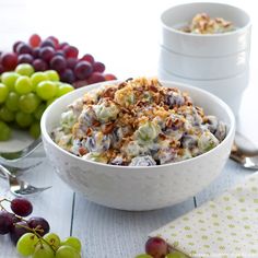 a bowl filled with grapes and nuts next to two white bowls full of grapes on the table