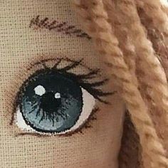 a close up of a doll's eye with long blonde hair