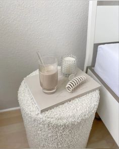 a table with two glasses and a book on top of it next to a bed