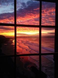 the sun is setting over the ocean from an open window