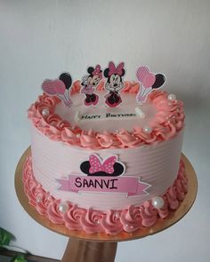 a birthday cake with pink frosting and minnie mouse decorations