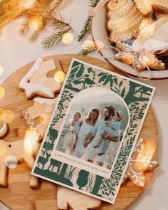 a christmas card sitting on top of a wooden plate next to cookies and other holiday decorations