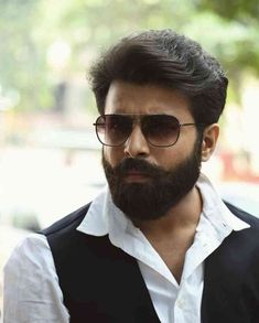 a bearded man with sunglasses and a vest