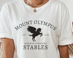 a woman wearing a t - shirt that says mount olympics, boarding and training stables