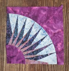 a purple and white fan sitting on top of a wooden table next to a piece of paper