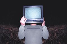 a man is holding up a small tv in front of his face with both hands