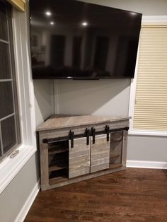 a tv mounted on the side of a wall next to a wooden cabinet and window