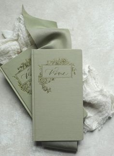 two wedding guest books on top of each other with a green ribbon tied around them