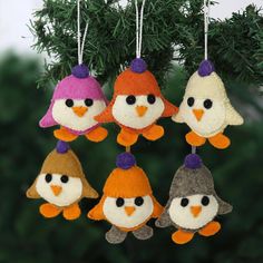 four little birds hanging from a christmas tree ornament with purple hats and orange beaks