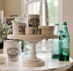 there is a cake stand with cups on it and some bottles next to the table