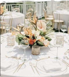 an arrangement of flowers and greenery on a table at a wedding reception with white linens