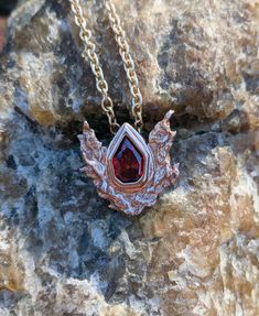 A 3D printed pendant based on the Goron's ruby from The Legend of Zelda: Ocarina of Time. The pendant is set with a 10x7mm ruby red cubic zirconia. Pictured pendant is printed in 14k rose gold plated. Symbolic Red Gemstone Jewelry, Symbolic Red Jewelry For Anniversary, Red Lab-created Ruby Pendant Jewelry, Red Symbolic Engraved Jewelry, Symbolic Red Pendant Jewelry, Unique Red Birthstone Jewelry, Unique Ruby Necklace For Gift, Collectible Red Ruby Jewelry, Red Garnet Pendant Jewelry