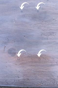 four white arrows pointing in different directions on a wooden surface with some paint peeling off