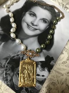 This is a handcrafted vintage assemblage necklace. I started with a goldtone finding, which looks like it has a little bo peep theme embossed on it.  Above it I added a green gemstone accent pin and then green beads on one side.  The opposite side has faux pearl rosary style beads. It is very unique and one of a kind !  No returns. Ship to continental US only. Unique Gold Necklaces From Vintage Collection, Unique Gold Vintage Necklace, Unique Gold Necklaces With Vintage Charm, Handmade Vintage Gold Necklace, Unique Antique Gold Necklace With Vintage Charm, Handmade Antique Gold Necklaces For Vintage Collection, Vintage Antique Gold Necklace, Handmade Antique Gold Necklace For Vintage Collection, Vintage Gold Necklace With Soldered Details