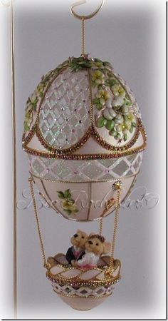 a white and gold ball shaped ornament with teddy bears in it's cage