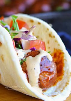 a taco filled with meat and vegetables on top of a wooden table