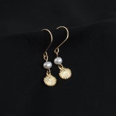 Who doesn't love pearls and seashells? These earrings combine the best of both worlds. You'll love the tiny shell charm and delicate freshwater pearl. A perfect gift for ocean lovers!   ABOUT: * Materials: 14k gold filled wire * Beads: real freshwater pearls and gold filled charm (one-sided, 7mm) * Earring wires: 22 gauge (.64mm) * Lightweight design * Sizing Details: (earring box is 2x3 inches for size reference) * Total Length: 1.25 in. (3cm) * Width: .25 in. (.5cm) SHOP OUR BRAND > https://ro Elegant Shell-shaped Jewelry With Pearl Charm, Shell-shaped Pearl Drop Earrings For Gifts, Elegant Nickel-free Shell Jewelry, Shell-shaped Pearl Earrings For Gift, Elegant Gold Shell With Pearl Charm, Ocean-inspired Dangle Pearl Drop Jewelry, Ocean-inspired Pearl Drop Dangle Jewelry, Elegant Pearl Charm Earrings With Shell, Elegant Shell Dangle Jewelry