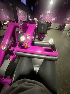 a person laying on top of a pink exercise bike in a room with purple walls