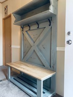 a wooden bench sitting in front of a wall mounted coat rack