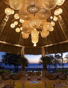 a large room with many lights hanging from it's ceiling and palm trees in the background