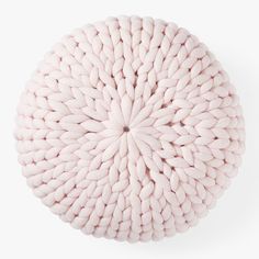 a pink knitted cushion on a white surface with the center circle shaped like a flower