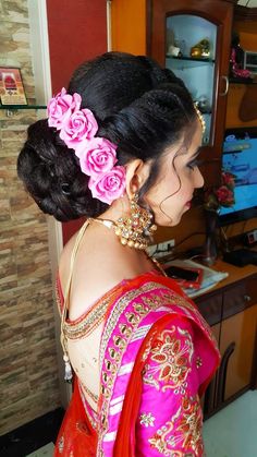 a woman in a red and pink sari with flowers on her hair is looking into the distance