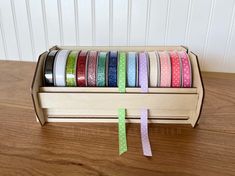 a wooden box filled with assorted colored washi tapes