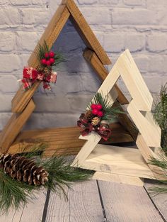 two wooden christmas trees with pine cones and bows on them sitting next to each other