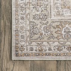 an area rug on top of a wooden floor with a white and brown design in the middle