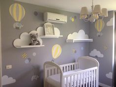 a baby's room decorated in gray and yellow with hot air balloons on the wall