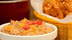 a white bowl filled with food next to a basket full of crackers and chips