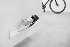 a pair of shoes is hanging on the wall next to a bike in a white room