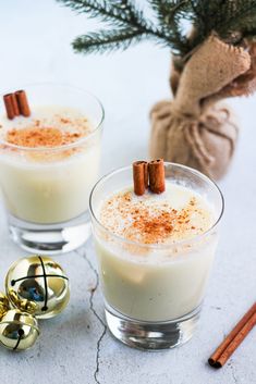 two glasses filled with white liquid and cinnamon sticks