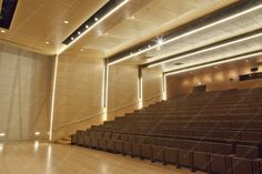 an empty auditorium with wooden seats and lights