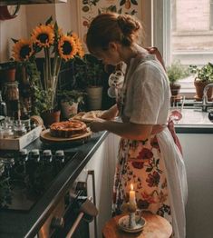 a woman standing in a kitchen preparing food on top of a counter next to a window