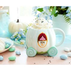 a white pumpkin shaped mug sitting on top of a table next to blue and white candies