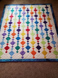 a multicolored quilt is on the floor in front of a carpeting area