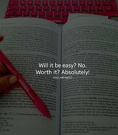 a person is holding a red pen in front of an open book with the words will it be easy? no, worth it't2 absolutely