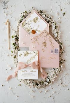 the wedding stationery is laid out on top of flowers