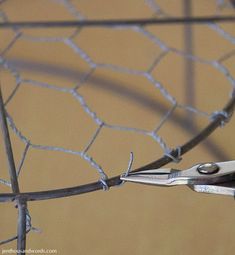 a pair of scissors is stuck in the wire fence that has been placed on top of it