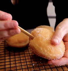 a person holding a donut in their hand with a stick sticking out of it