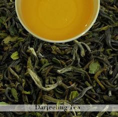 a white bowl filled with green tea next to a pile of black and white leaves