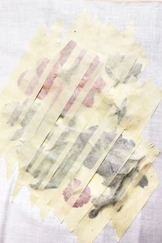 torn pieces of paper sitting on top of a white cloth covered in pink and grey paint