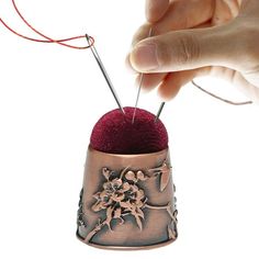 a person is knitting yarn on top of a small object with two needles in it