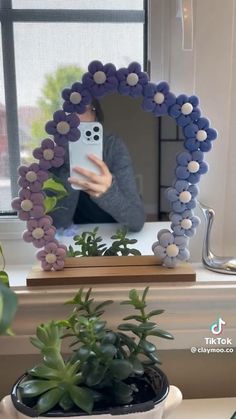 a woman taking a selfie with her phone in front of a flowery mirror