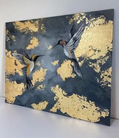 two birds flying in the sky with gold paint